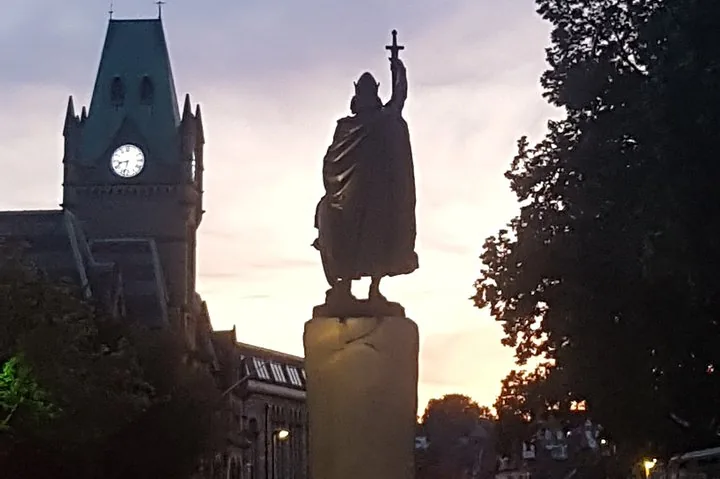 A silhouette of a statue against a sunset sky.
