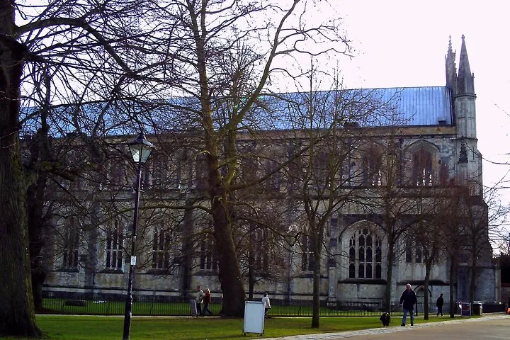 A large building with a dark roof and large trees in front.